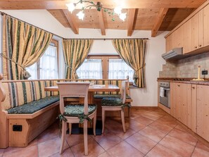 Una cocina acogedora con armarios de madera, una mesa de comedor con bancos y un banco empotrado con cojines.