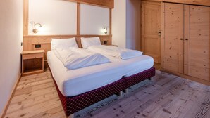 Een slaapkamer met houten meubels, een bed, nachtkastjes en een garderobe.