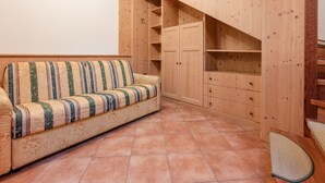 Een kamer met een bank, houten kasten en een betegelde vloer.