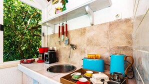 A kitchen with a window overlooking greenery, a sink, a toaster, and a tray with various kitchen items. - Villa Piano - Four Bedroom Villa With Terrace and Swimming Pool (Zupa dubrovacka)