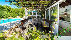 A covered patio with a pool, a dining table, and wicker baskets. - Villa Piano - Four Bedroom Villa With Terrace and Swimming Pool (Zupa dubrovacka)