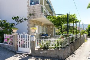 Een woonhuis met een verharde oprit, een poort en een balkon, plus een klein terras met buitenmeubilair.