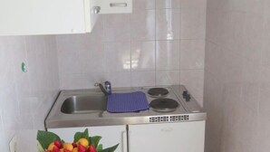 A compact kitchen with a stainless steel sink, a stove, and a small refrigerator. - Apartments Franka - Studio With Terrace and Sea View (Dubrovnik)