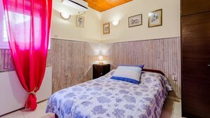 Un dormitorio con cama, mesita de noche y ventana con cortinas rojas.