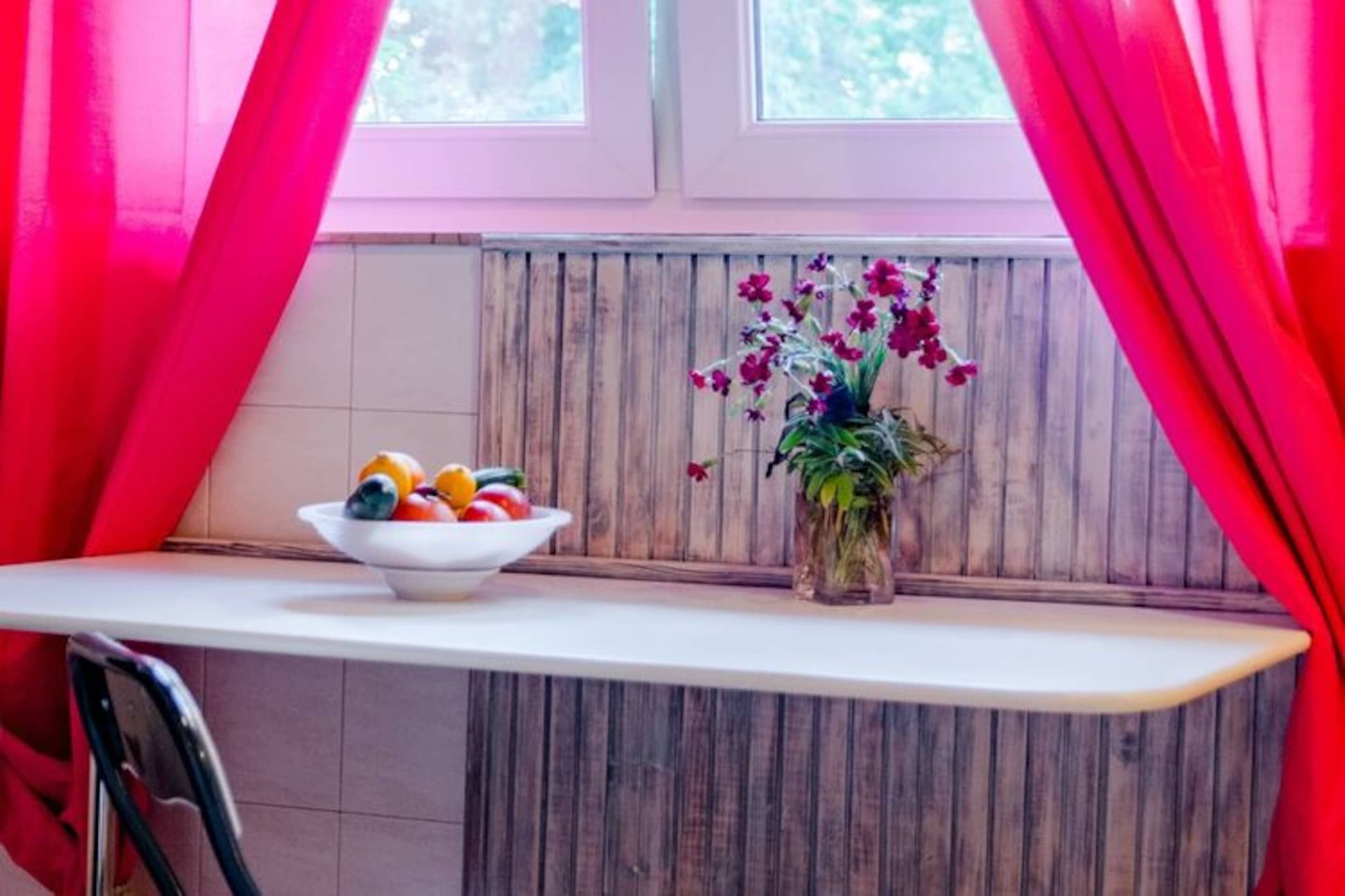 A kitchen counter with a bowl of fruit and a vase of flowers.