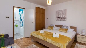 A bedroom with a bed, bedside tables, a painting, and a bathroom visible through an open door. - Sunset Bay Room - Double Room With Terrace and Partial Sea View (Dubrovnik)