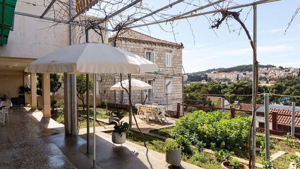 A covered outdoor seating area with umbrellas, potted plants, and a view of a town. - Sunset Bay Room - Double Room With Terrace and Partial Sea View (Dubrovnik)