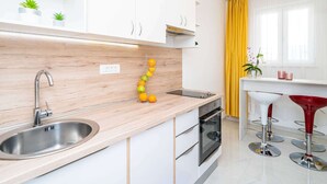 A modern kitchen with white cabinets, a wooden countertop, a stainless steel sink, and a yellow curtain. - Apartments Blazevic - Comfort Two Bedroom Apt With Hot Tub and Sea View (Zupa dubrovacka)