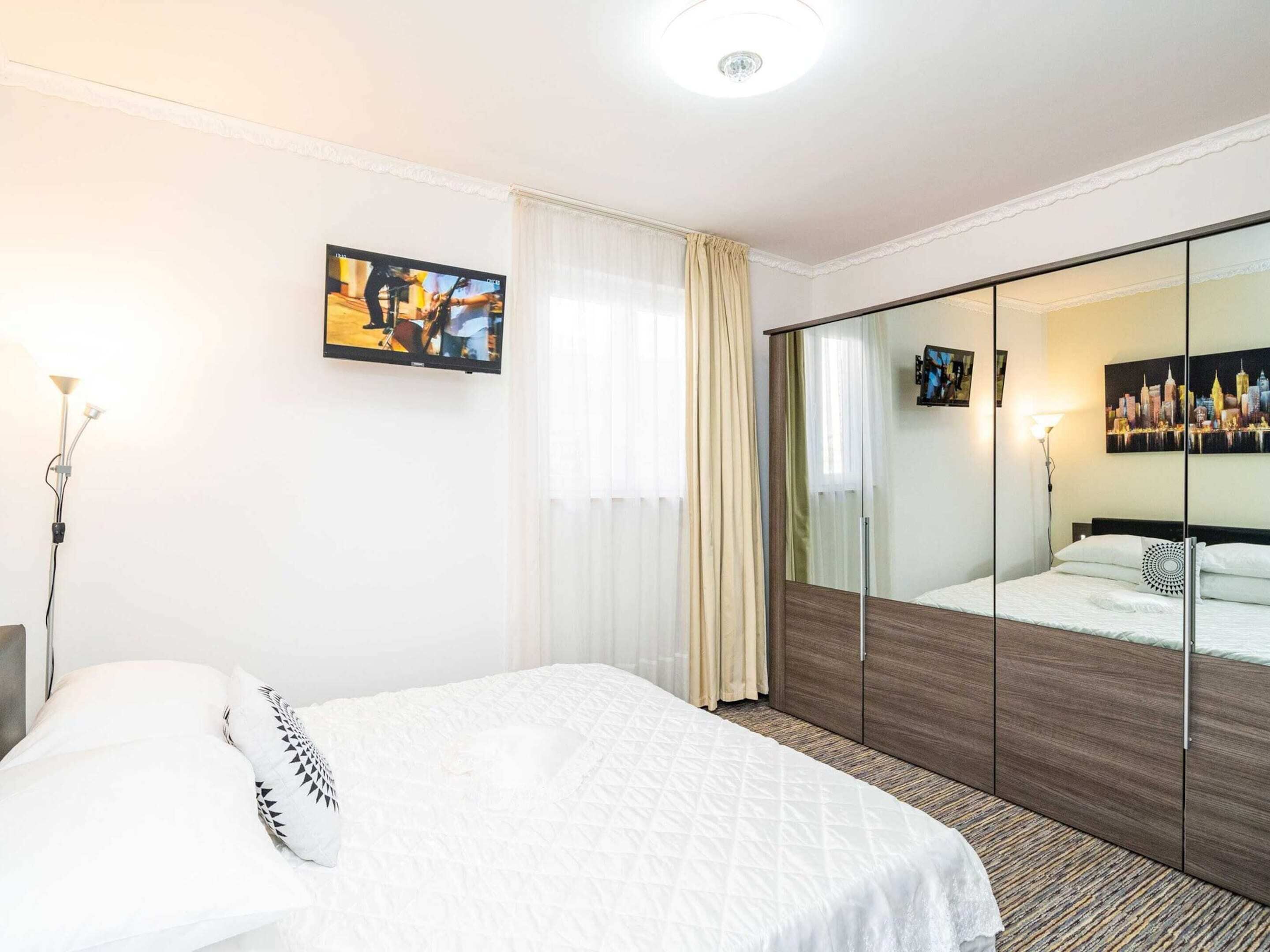 Ein Hotelzimmer mit Bett, großem Spiegel, einem Gemälde und Blick auf die Stadt.