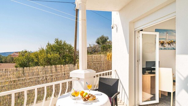 A balcony with a table set for breakfast, a chair, and a view of the countryside. - Apartments Blazevic - Comfort Two Bedroom Apt With Hot Tub and Sea View (Zupa dubrovacka)
