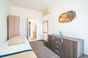 Ein Hotelzimmer mit Bett, Kleiderschrank, Schminktisch und Spiegel sowie einer Wanddekoration.