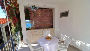 A balcony with a round table and two chairs, a small window, and a view of the sea. - Apartments Mediterranean House - Two Bedroom Apartment With Terrace (Slivno)
