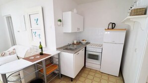 A compact kitchen with a dining table, a sink, a stove, and a refrigerator. - Apartments Mediterranean House - Two Bedroom Apartment With Terrace (Slivno)
