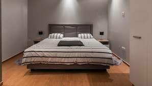 Een moderne slaapkamer met een groot bed, twee nachtkastjes en een hoofdbord.