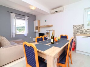 A modern dining area with a wooden table, blue upholstered chairs, and a bottle of wine. - Apartments Radojkovic Lumbarda - Comfort Two Bedroom Apartment With Terrace and Sea View (Lumbarda)