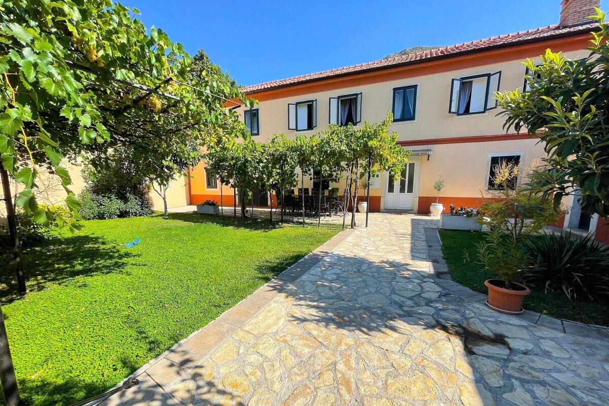 A courtyard with a stone pathway leading to a building with multiple windows and a tiled roof.