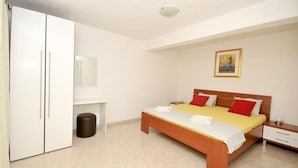 Ein Schlafzimmer mit Bett, Nachttischen, einem Kleiderschrank und einem Mülleimer.