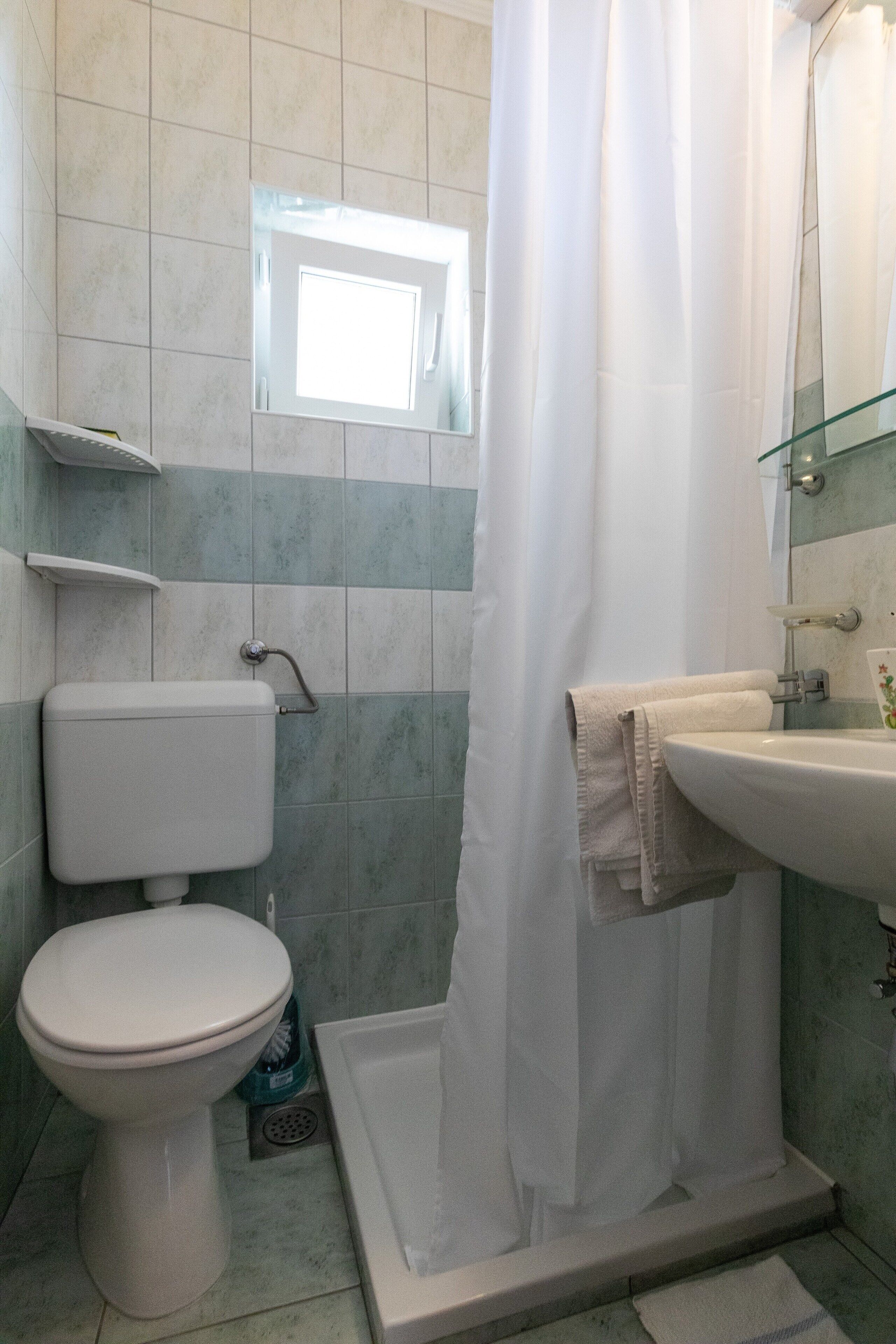 A bathroom with a toilet, shower, and sink.