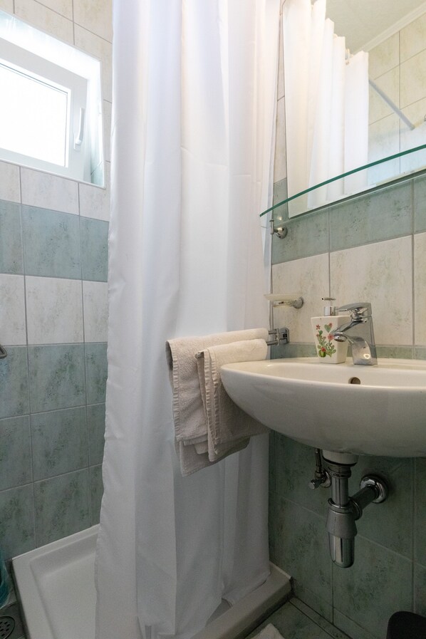A bathroom with a white sink, a glass shower enclosure, and a mirror above the sink.