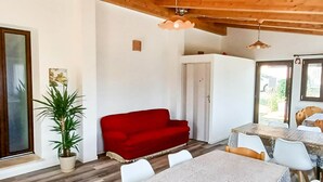 A dining area with a table and chairs, a red sofa, and a potted plant. - Villa in Montefalcone Appennino With Swimming Pool (Montefalcone Appennino)