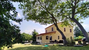 A two-story yellow building with a swimming pool, outdoor seating, and a large tree in the foreground. - Villa in Montefalcone Appennino With Swimming Pool (Montefalcone Appennino)