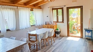 A dining area with a wooden table and chairs, a kitchen area with a window, and a door leading to an outdoor space. - Villa in Montefalcone Appennino With Swimming Pool (Montefalcone Appennino)