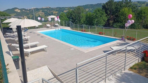 A rectangular swimming pool with a clear blue water surface, surrounded by a tiled deck area with lounge chairs and umbrellas. - Villa in Montefalcone Appennino With Swimming Pool (Montefalcone Appennino)