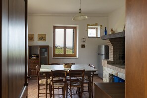 A dining area with a table and chairs, a brick fireplace, and a window with a view of the countryside. - Classic Villa for Family With Pets (Bevagna)