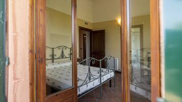 A bedroom with a metal bed frame, a wooden door, and a tiled floor.