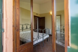 A bedroom with a metal bed frame, a wooden door, and a tiled floor. - Classic Villa for Family With Pets (Bevagna)