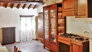 A rustic kitchen with wooden cabinets, a gas stove, and a radiator. - Belvilla by OYO Mansion in Orvieto (Orvieto)