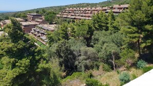 A residential area with multiple two-story buildings, surrounded by dense greenery and hills in the background. - Apartment in Sardinia With Stunning Sea View (Olbia)
