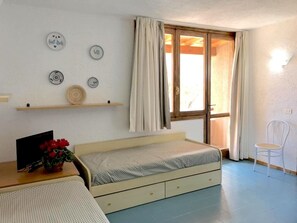 A bedroom with a bed, a desk with a chair, a window with curtains, and wall decorations.