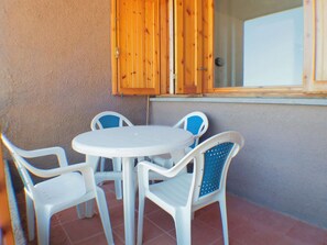 Un pequeño patio al aire libre con una mesa redonda y cuatro sillas.