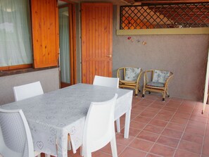 Um pátio com mesa e cadeiras, portas de madeira e uma parede com decoração vazada.