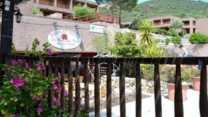 A restaurant with outdoor seating, surrounded by greenery and a hillside. - Apartment in Olbia With Garden (Olbia)