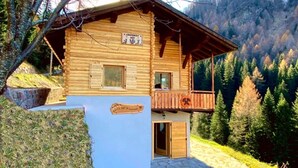 Eine Holzhütte mit Balkon, ein Schild, das sie als Berghütte kennzeichnet, und ein Steinweg, der dorthin führt.