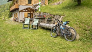 Eine Blockhütte mit einem Balkon, einem Fahrrad und Sitzgelegenheiten im Freien.