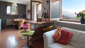 A modern living room with a dining area, large windows with a view, and a cozy seating arrangement. - Belvilla by OYO Corno Nero (Ville di Fiemme)