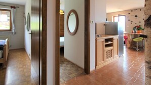 A compact kitchen with a refrigerator, a wooden cabinet, and a dining area with a chair. - Belvilla by OYO Corno Nero (Ville di Fiemme)