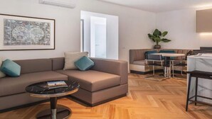 A modern living room with a sofa, coffee table, and a dining area with a table and chairs.