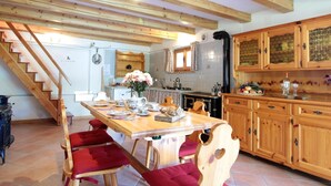 A spacious kitchen with wooden cabinets, a dining table with chairs, and a staircase leading to an upper level. - Belvilla by OYO Casera Pantonio (Fonzaso)