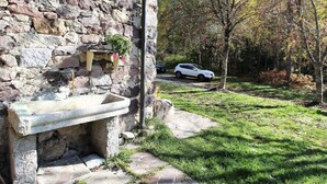 A stone building with a stone bench and a planter with flowers. - Belvilla by OYO Baita Silana (Pieve Tesino)