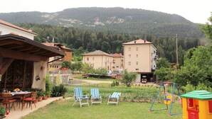 A residential area with a grassy yard, a wooden pergola, and a swing set. - Family Retreat Near Garda (Ronzo-Chienis)