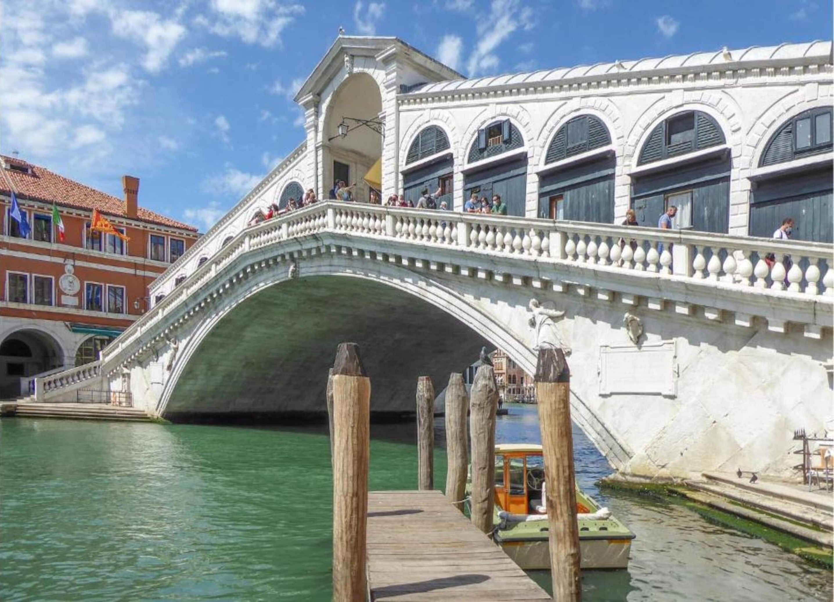 A historic stone bridge with a wooden walkway leading to a boat.
