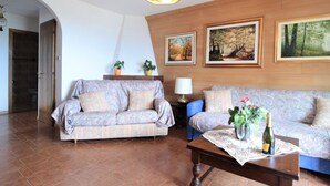 A living room with a sofa, a coffee table with a bottle and glasses, and two potted plants. - Large Apartment With Terraces in Val di Fiemme (Ville di Fiemme)