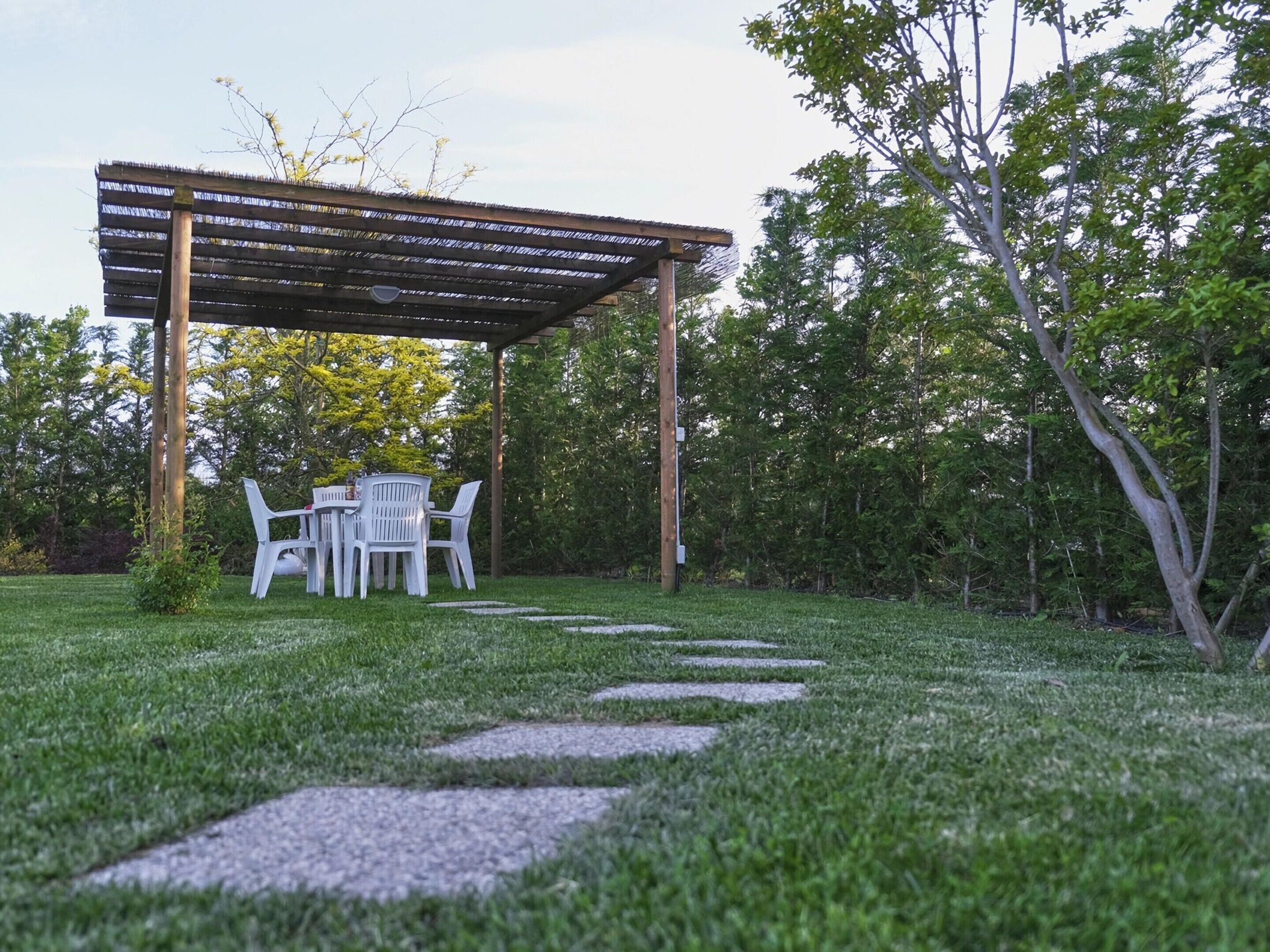 A garden patio with a pergola, a table, and chairs.