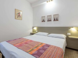 Ein Hotelzimmer mit einem Bett, zwei Nachttischen und drei an der Wand befestigten Kunstwerken.