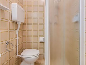 Ein Badezimmer mit Toilette, Handtrockner und Papierhandtuchspender.