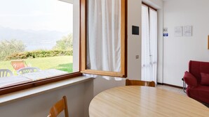 Une pièce avec une table et des chaises en bois, une fenêtre avec des rideaux et une vue sur un paysage verdoyant.